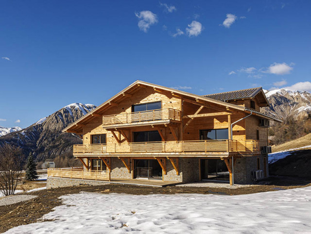 Three-storey wooden chalet, wooden terraces, French windows, courtyard, open space, view of snow-capped mountains