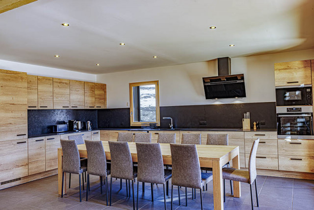 Large bright and cosy chalet living room, kitchen, TV, dining table, wood furniture, tiled floor, window