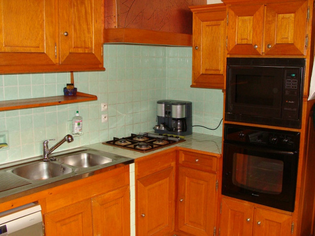 Kitchen area with wooden furniture, gas hobs, oven, microwave, tiled walls