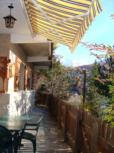 Exterior terrace of a house made out of stone, wooden fence, outdoor table, autumn scenery