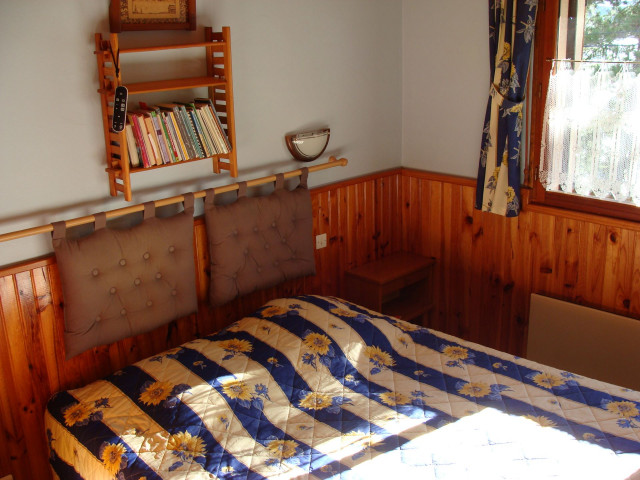 Bright bedroom with double bed, wooden furniture and panelling, window and curtains