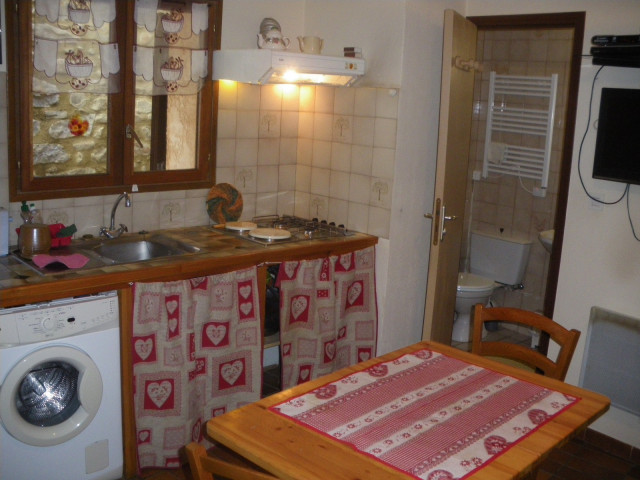 Coin séjour avec cuisine, table à manger, évier, machine à laver, carrelage au mur, ameublement bois, porte vers salle de bains - © J Matheron Coin séjour avec cuisine, table à manger, évier, machine à laver, carrelage au mur, ameublement bois, porte vers salle de bains