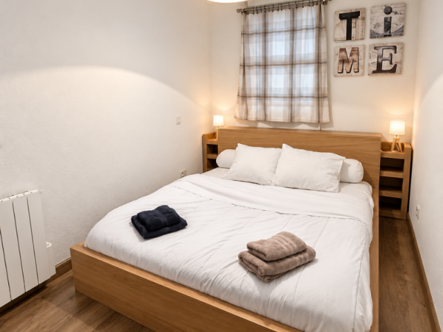 Une chambre moderne et chaleureuse avec un grand lit en bois, un éclairage doux et un parquet en bois. - © C.Travaglini Une chambre moderne et chaleureuse avec un grand lit en bois, un éclairage doux et un parquet en bois.